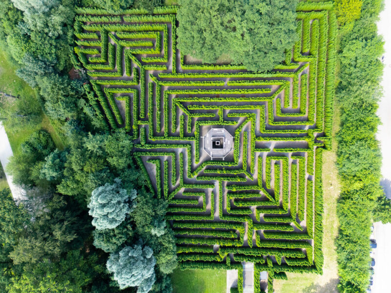 Draufsicht auf einen großen Irrgarten aus Hecken mit Aussichtsplattform im Zentrum